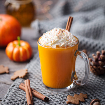 Pumpkin latte with spices and whipped cream. Grey background. Close up.