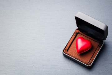 Heart shaped chocolate candy in a gift box on slate background. Top view. Copy space.