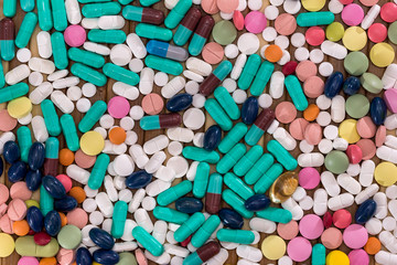 Colourful tablets dispersed on wooden table closeup