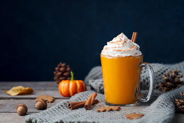 Pumpkin latte with spices. Boozy cocktail with whipped cream on top on a wooden background. Copy space.