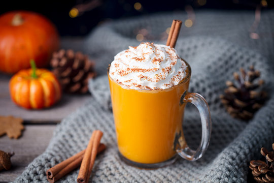 Pumpkin latte with spices. Boozy cocktail with whipped cream on top on a wooden background.