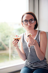 girl eating tasty cakes, sitting by the window, sweet food and pleasure