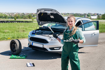 Mechanic woman standing on the background of car with tools