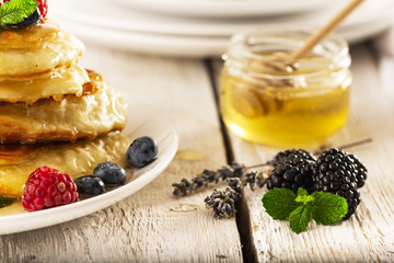 Pancakes with forest fruits berries on white table.