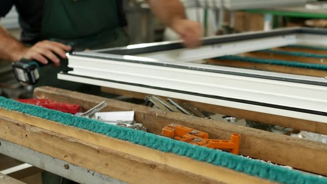 Production and manufacturing of pvc windows, the male worker assembles a pvc profile window, fastens the hinged parts, pvc window, screwdriver window