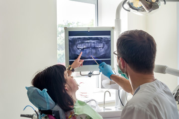 Dokter tandarts wijzend op de röntgenfoto van de patiënt op monitor