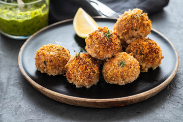 Homemade meatballs with thyme and green sauce on a black plate. Copy space.