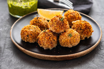 Homemade meatballs with thyme and green sauce on a black plate. Copy space.