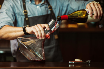 Sommelier pouring red wine into carafe to make perfect color