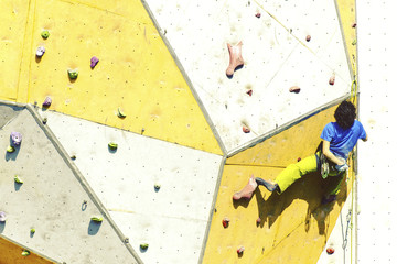 Man bouldering at an indoor climbing centre. Climber practicing rock climbing at an indoor climbing gym.