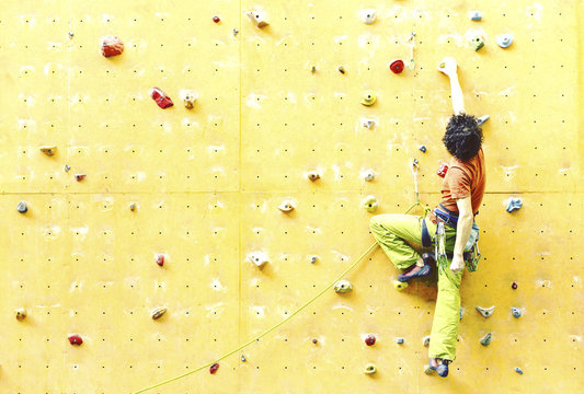 Man bouldering at an indoor climbing centre. Climber practicing rock climbing at an indoor climbing gym.