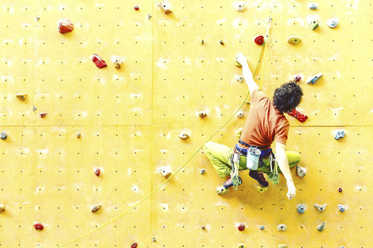 Man bouldering at an indoor climbing centre. Climber practicing rock climbing at an indoor climbing gym.