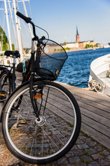 Fototapeta premium Bicycle parked by waterfront with boats and historic European cityscape in soft evening light