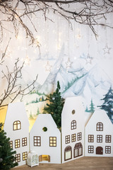 Naklejka premium The decor in the children's room for Christmas. Cardboard houses, mountains on the wall, tree with Christmas garland