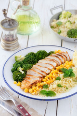 Deconstructed healthy chicken and couscous salad with broccoli florets and corn or Buddha bowl
