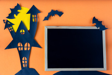 Halloween concept with haunted house castle and blackboard on orange background