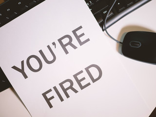 Dismissal letter on white office desktop. You are fired
