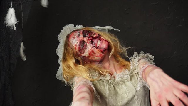 Horrifying spooky dead bride scary zombie wedding wife creepy young blonde woman wearing professional Halloween makeup