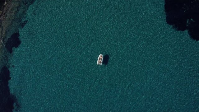 Aerial shot of happy couple relaxing and sunbathing on a boat parked in the middle of the most clean Mediterranean water on a warm summer day. Top travel destination. Vacation in Croatia. 