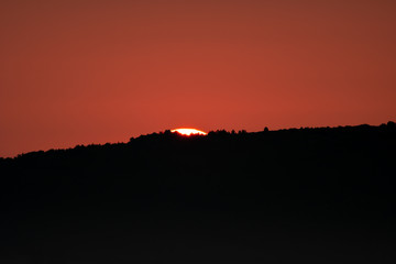 Sun rising behind the dark mountain a little bit