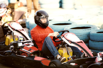 Young man is driving go-kart car with speed in a playground racing track - go kart is a popular leisure motor sports - obrazy, fototapety, plakaty