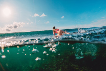 Attractive surfer woman in ocean and wave. Surf girl make duck dive.