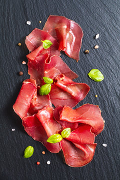 Food concept Sliced Dried Cured beefs Bresaola on black slate stone board
