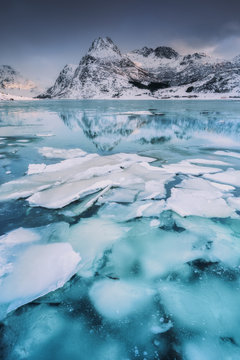 Vue sur une montagne enneig&eacute;e au lever du soleil et son reflet avec en pemier plan des morceaux de glaces