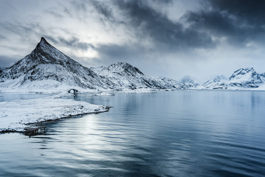 Vue en hauteur de la montagne pointue &agrave; Fredvang avec son pont reliant le village de p&ecirc;che de Fredvang sur l'&icirc;le de Moskenesoya &agrave; l'&icirc;le voisine de Flakstadoya