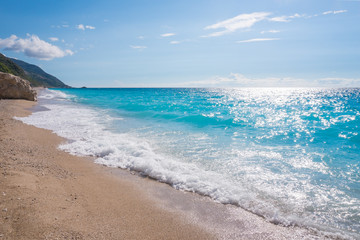 Fototapeta na wymiar Blue ocean shore with golden sands and rocks