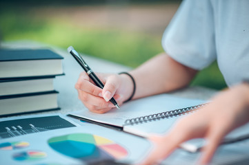 Woman sitting at desk and working at hand of book and financial documents close up