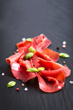 Food concept Sliced Dried Cured beefs Bresaola on black slate stone board