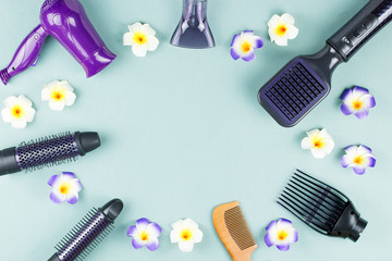 Hairdressing tools with flowers on blue wooden background