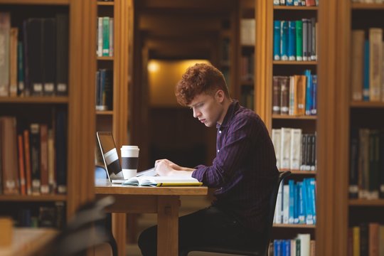 College student reading a book in library