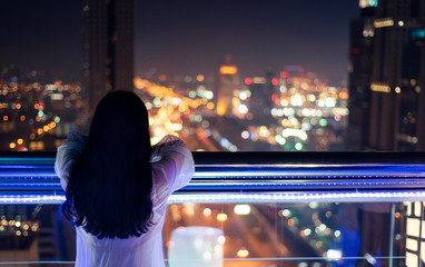 Woman enjoying night city view from the balcony