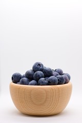 Side view of wooden bowl full of ripe juicy blueberries in wooden bowl isolated on white background with plenty of copyspace