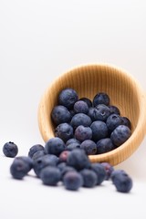 Ripe juicy beautiful blueberries in wooden bowl isolated on white background