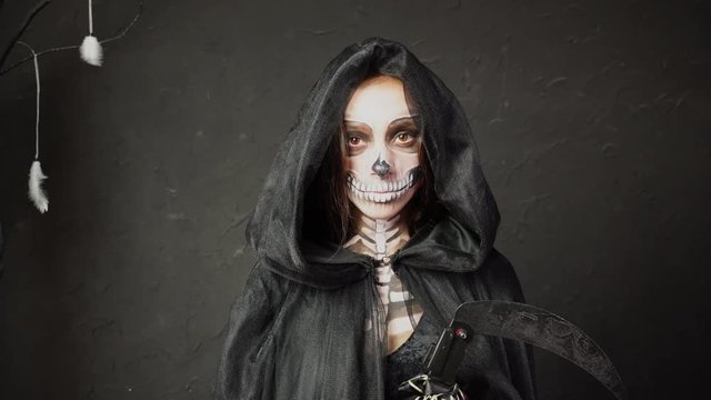 Scary spooky creepy Skeleton female in Death Reaper cape Halloween costume heavy professional makeup approaching camera