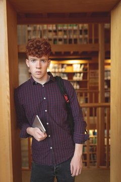Portrait of college student with digital tablet in library