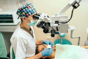 Dentist examine oral cavity of female patient with microscope. - obrazy, fototapety, plakaty