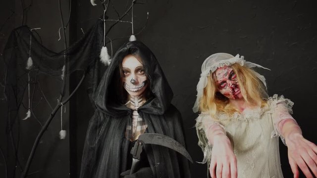 Scary dead bride spooky zombie wife and creepy Death Reaper woman wearing impressive heavy professional Halloween makeup