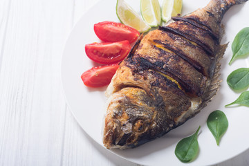 Fried fish dorado with lime , tomatoes and spinach