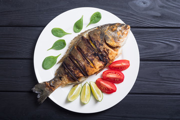 Fried fish dorado with lime , tomatoes and spinach