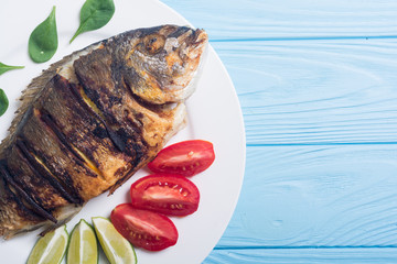 Fried fish dorado with lime , tomatoes and spinach