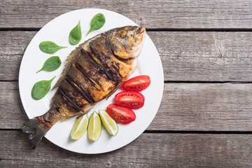 Fried fish dorado with lime , tomatoes and spinach