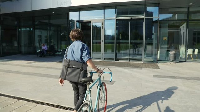 Successful, rich man comes to work by bike on sunny morning, concept of healthy lifestyle and living green