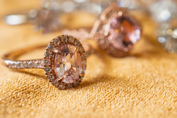 Jewelry pink diamond rings on golden fabric background close up