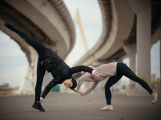 Girls begin to perform a synchronized jump in the splits on the urban background of the bridge