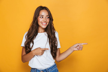 Young pretty woman posing isolated over yellow background showing copyspace. - obrazy, fototapety, plakaty