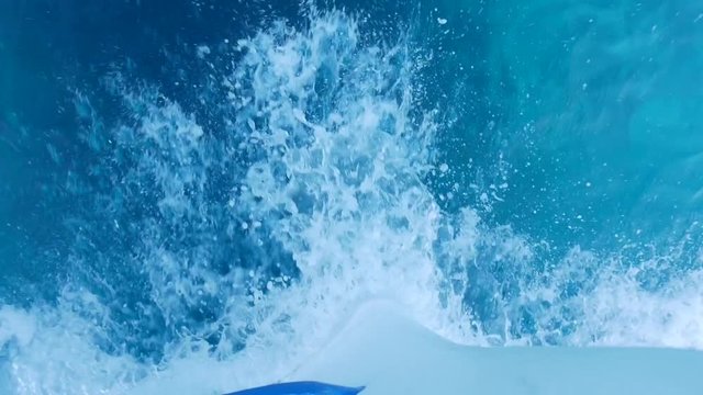 View looking over the front of a speeding boat at the waves and wake in the water